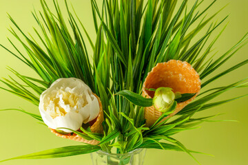Close-up Ice cream cone for ice cream with white peony flower on green background. Festive creative concept for birthday, mother's day, valentine's day.