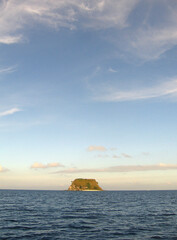 Vertical shot of a small island in the sea with a beautiful sky view © Mark Kucharski/Wirestock