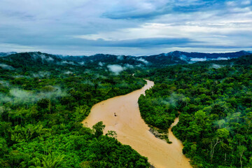 Aerial view over a tropical river in the rainforest with the trees of the tropical forest being covered in a layer of fog