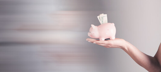 hands hold a piggy bank with a bill