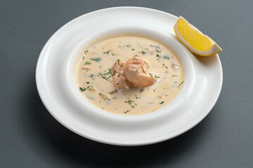 finnish creamy soup with salmon fish and dill in white plate on grey background