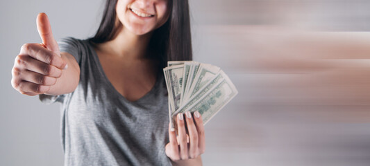 young girl holding money and showing thumb up