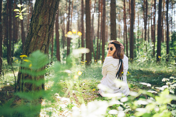 Young beautiful hippie woman walks in the summer forest laughs dances and enjoys life and nature