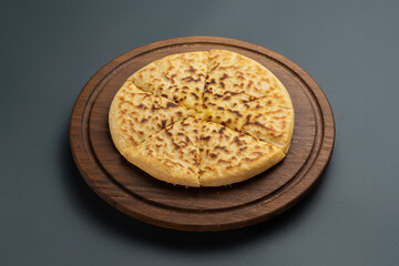 sliced megrelian khachapuri with cheese on wooden board on grey background