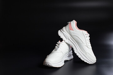 White sneakers on black with copy space. Training shoes on black background.