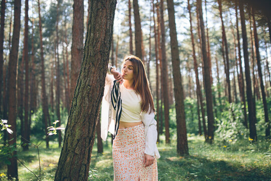 Young beautiful hippie woman walks in the summer forest laughs dances and enjoys life and nature