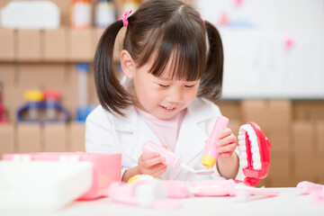young  girl pretend play dentist role at home