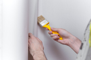 Young professional repairman glueing wallpapers on concrete wall. Repair apartment. Home renovation...
