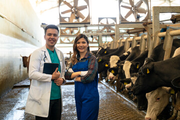 Portrait of vet with digital tablet and farmer smiling on dairy farm