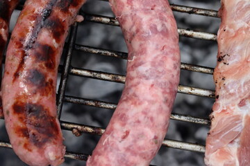 Close-up of sausage and pork meat grilling on the grill.
