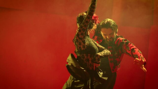 Beautiful couple dancing latin dance . Professional dancers dancing flamenco, rumba or salsa on red background. Pair in spanish dress performs dance movement. Shot ARRI ALEXA Camera in Slow Motion 