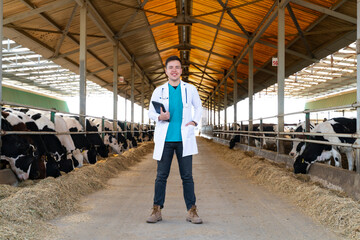 cheerful veterinarian standing with digital tablet in cowshed