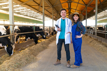 Young farmer and veterinarian standing on dairy farm