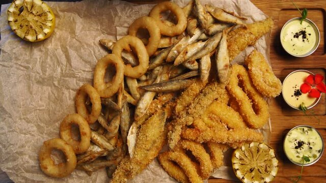 Timelapse of chef serving deep fried fish mix food set composition. Cook puts squid rings, sprat, gobies, oysters on a tray in luxury asian restaurant. Delicious snacks and sauces in cafe.