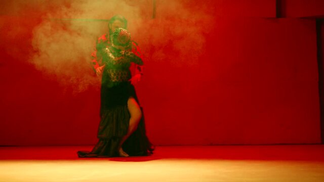 Beautiful couple dancing latin dance . Professional dancers dancing flamenco, rumba or salsa on red background. Pair in spanish dress performs dance movement. Shot ARRI ALEXA Camera in Slow Motion 