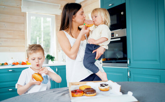 A happy family ordered donuts with home delivery. They eat desserts in the kitchen.