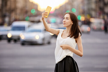 Woman video blogger uses smartphone to report from city street.