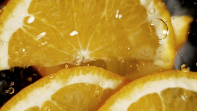 Orange slices are falling into a water in slow motion. Water splashing on fresh orange. Water dropping from citrus fruit. Close up orange slice rich in vitamin C.