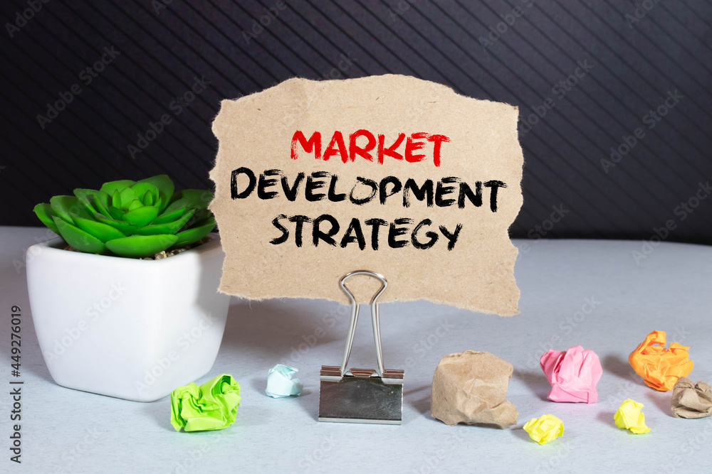 Poster market development strategy text written on a notebook with pencils