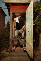 Man using wooden toilet latrine on summer cottage