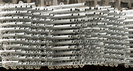 Side view of piles of aluminium construction pipes.