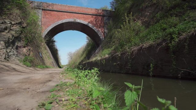 A high brick bridge over a canal with shallow focus weeds