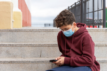 boy with mask using mobile phone