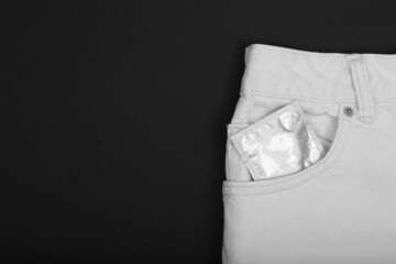 Condom in package in white jeans. Men found condoms to prevent sexually transmitted infections or...