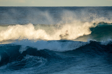 waves crashing in the ocean with the sun light on them