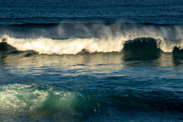 waves crashing in the ocean with the sun light on them