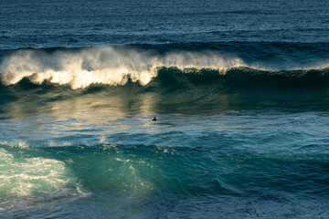 wave breaking in the ocean with Bodysurfer swimming in the waves 