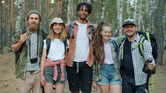 Portrait of happy men and women hugging looking at camera standing in forest together smiling. Healthy active lifestyle and friendship concept.