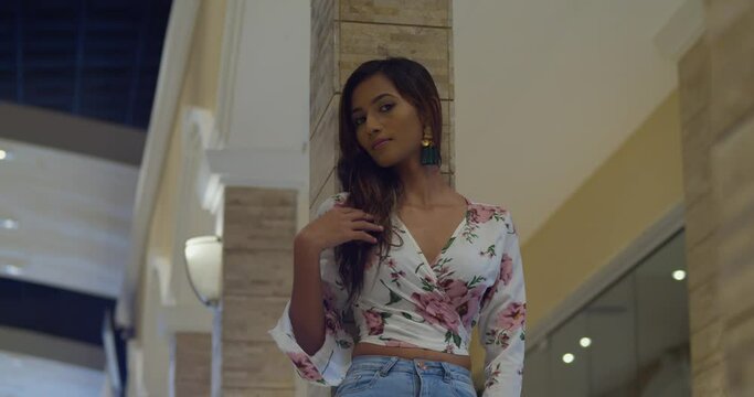 Low angle view of a young woman playing in her hair at an urban mall