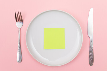 Colored Sticky Note or Memo Paper on White Ceramic Plate Lying On Pink Background - Top View, Flat Lay