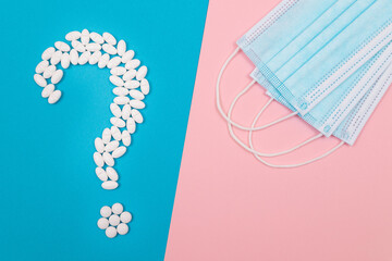 Question Mark Made from White Pills and Tablets with Medical Face Masks, Lying on Split Blue and Pink Background. Global Pharmaceutical Industry and Medicinal Products
