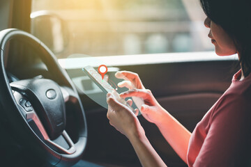 Woman searching destination or gps on smartphone inside car.