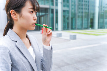 電子タバコを吸う若いビジネスウーマン