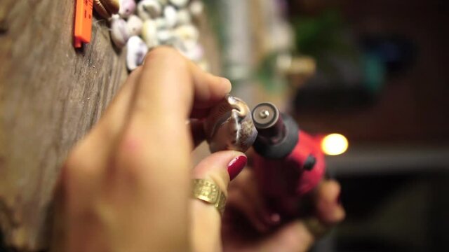 Craftsman shaping sea shell to make jewelry, close up vertical video