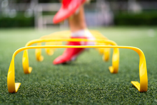 A yellow step-over ladder for speed and leg strength training equipment (Focus), Photo with action of a sport player is training on it as blurred background. Sport object and action photo.