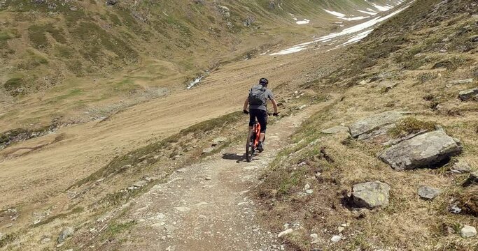Mountain biking on a single trail with a enduro MTB in high alpine terrain. Follow camera mountain biking  in the austrian alps tirol with friends. Close up MTB riding on rocks and dirth 4K