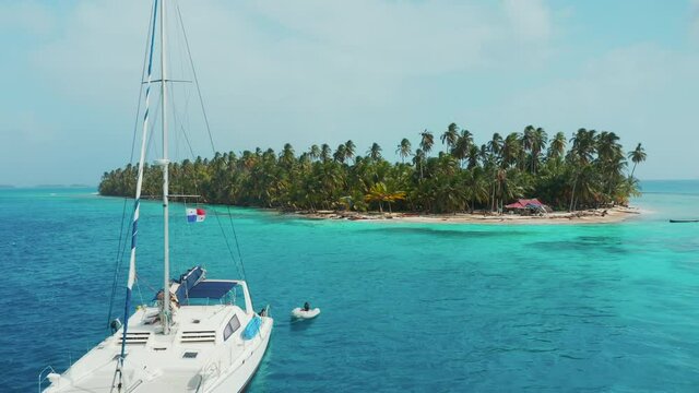 Sailboat Floating Near A Beautiful Tropical Island With Palm Tree Forest By The Caribbean Sea. San Blas Islands In Panama. drone shot