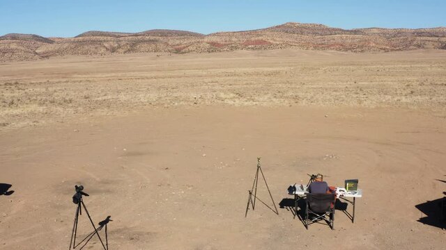Aerial view of western landscape in Norwood, Colorado where a man sitting on a table and firing a riffle.