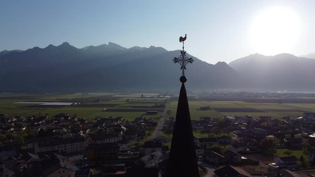 Aerial subject and fly by shot of a steple on a church in Vionnaz, Switzerland on a sunny day.