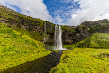 Typical landscape for the summer in Iceland. At the foot of the waterfall Seljalandsfoss crowds of tourists