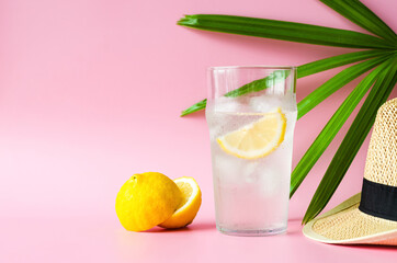A glass of lemonade soda with hat and lady palm leaf on pink background. Summer drink concept. - obrazy, fototapety, plakaty