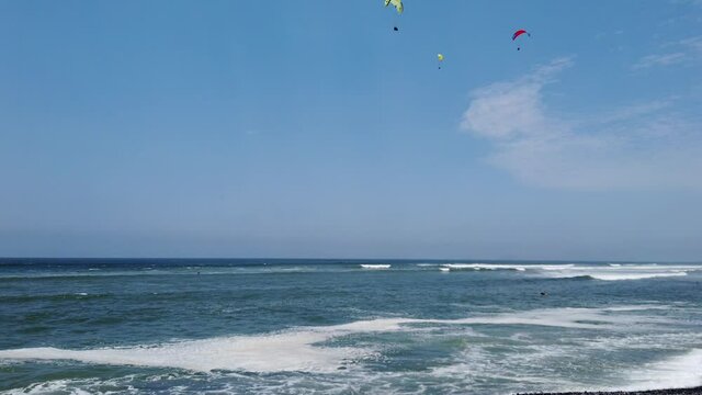 4k video with 3 people paragliding over the windy coast of the Pacific ocean in the capital city of Lima, Peru. Tilt down over the ocean, 60 fps