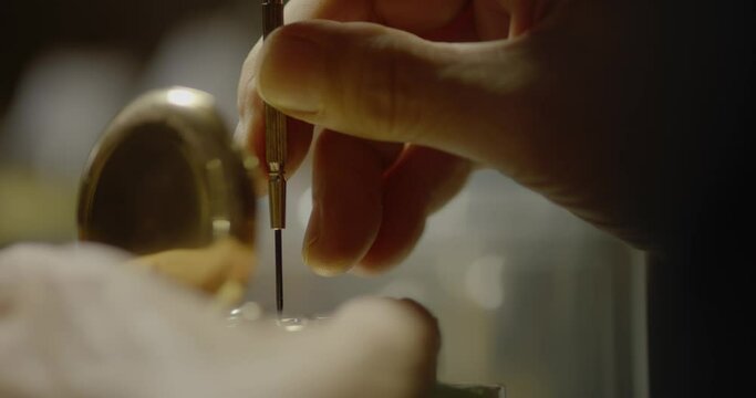 Person using fine tool to work on a pocket watch