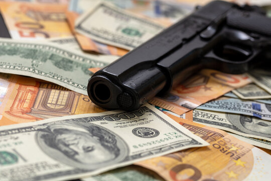 Criminal money. Pistol on dollar and euro banknotes background. Mafia and corruption concept,