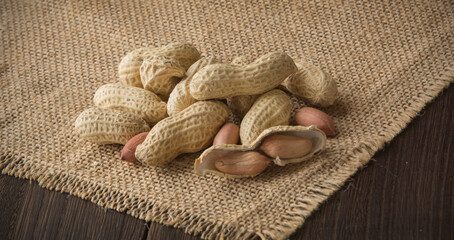 Wooden plate with peanuts on a burlap base for background 