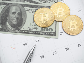 Money dollar pen and gold bitcoin on calendar